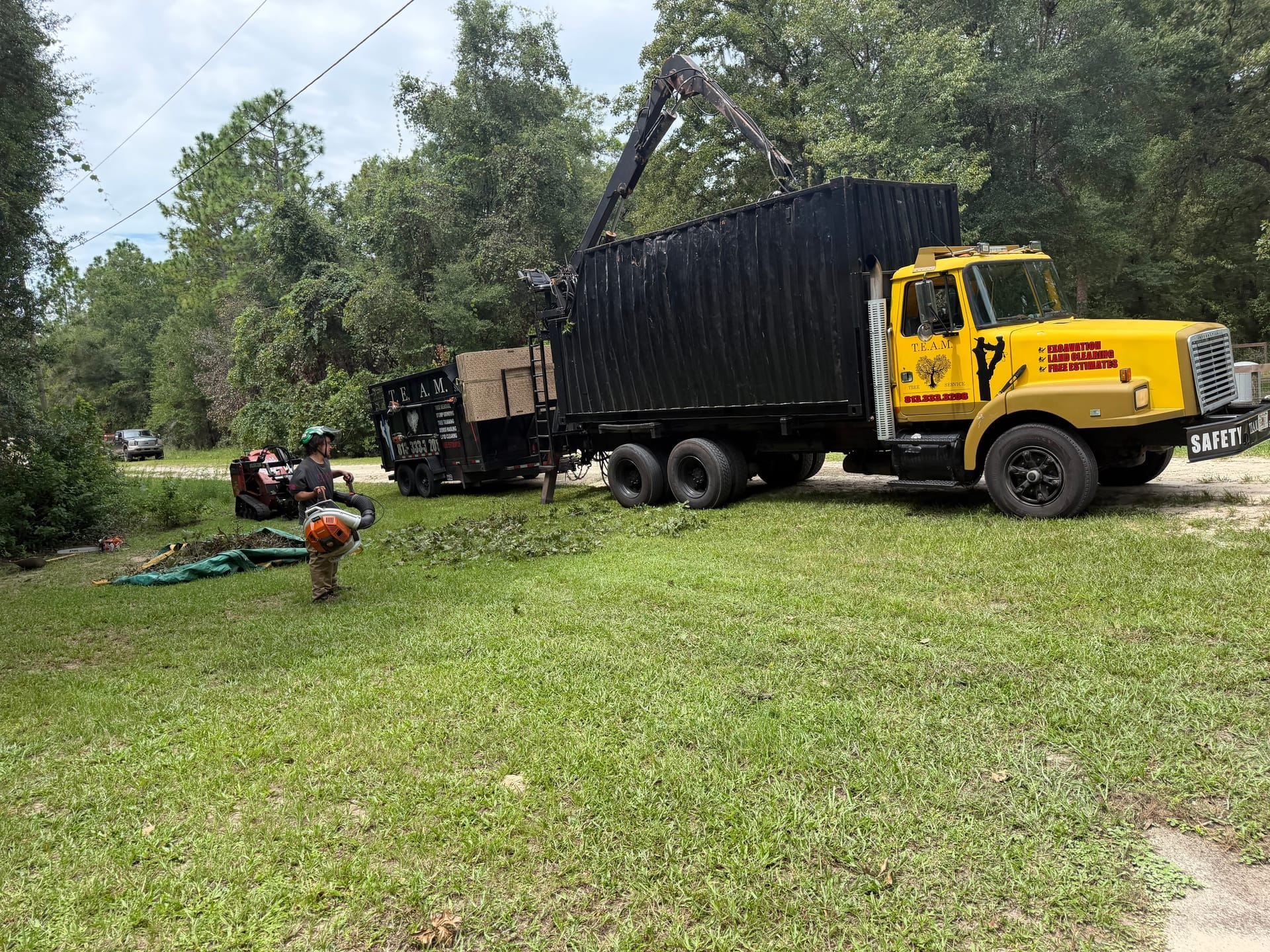 T.E.A.M. grapple truck, dump trailer, and crew cleaning up a Tampa Bay job