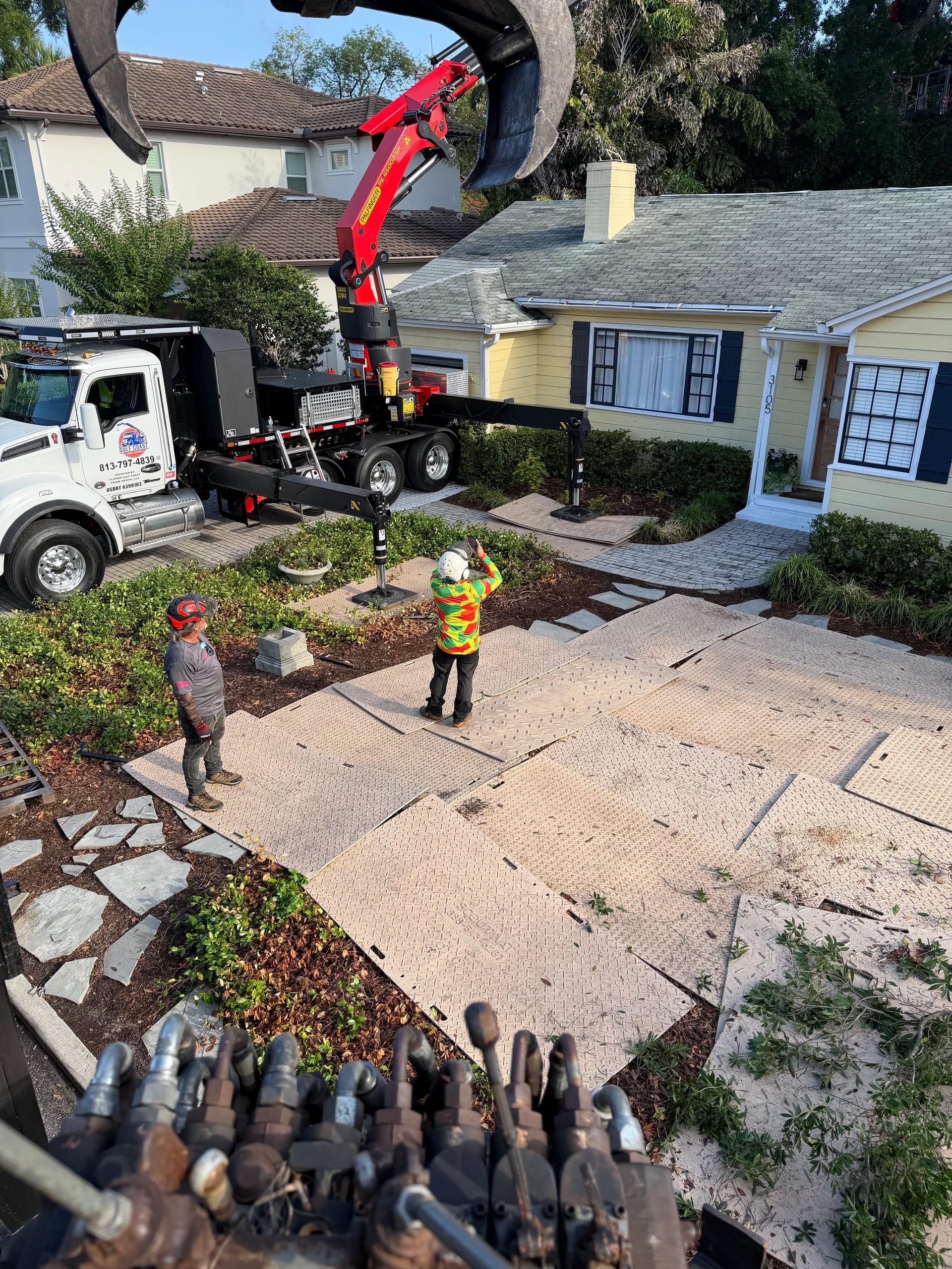 Crew protecting a driveway with ground mats during a crane-assisted tree removal